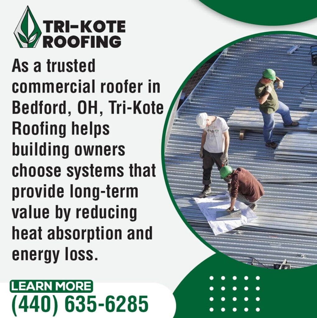 Three roofers on a large commercial roof structure, which appears to be a metal roof in progress. One roofer in a green hard hat kneels, examining plans, while the other two stand, observing. The structure shows exposed metal framing.
